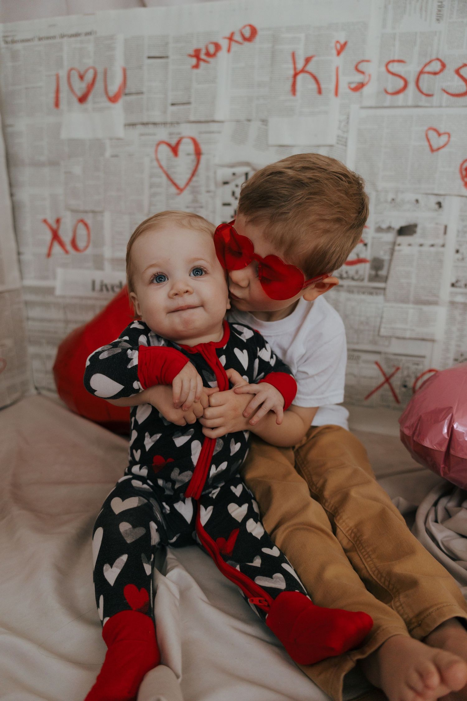 A festive Valentine's scene with red hearts drawn on a white backdrop and decorative balloons.