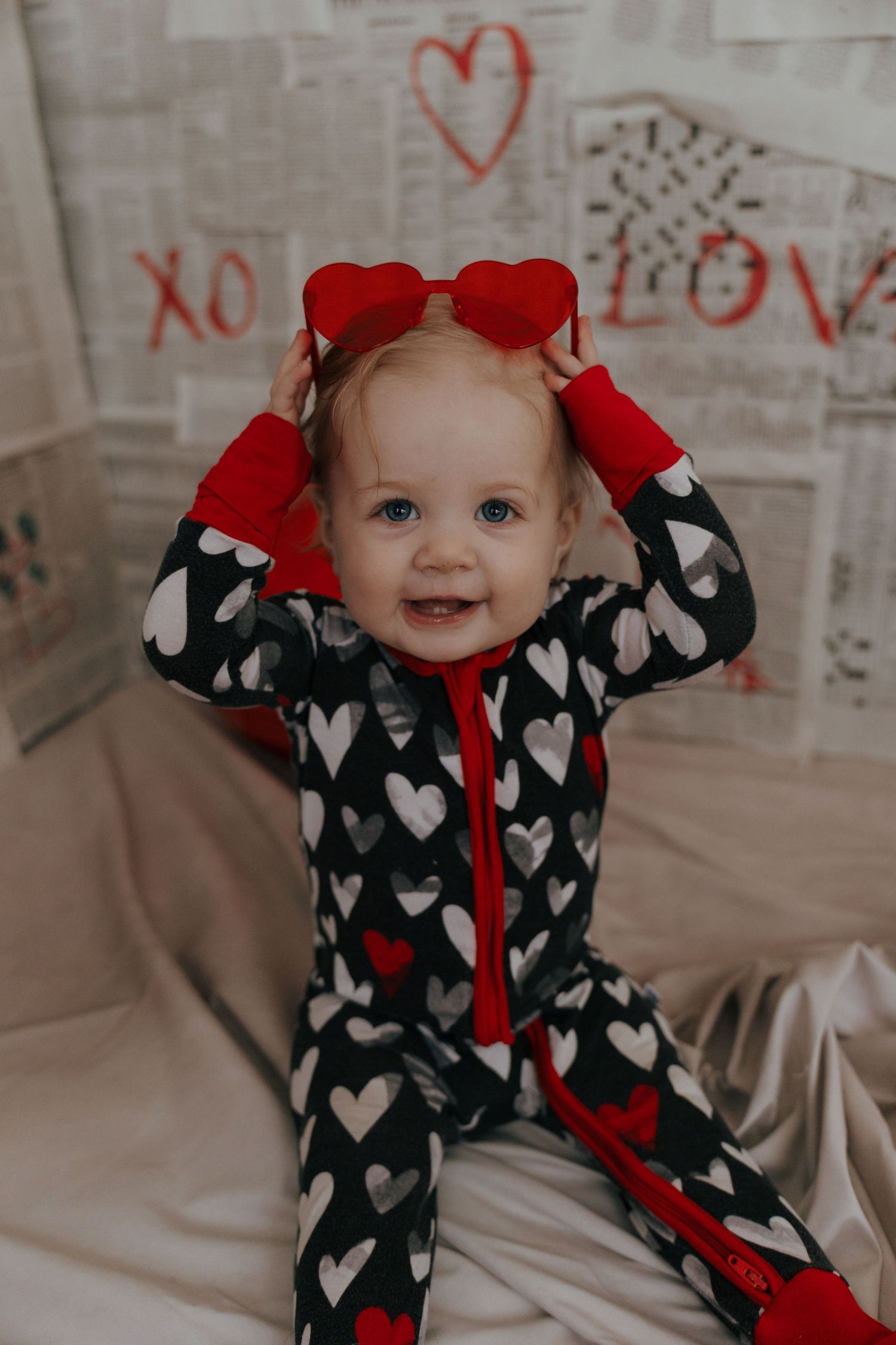 Valentine's themed photo with heart decorations and heart-patterned outfit with red bow accessories.