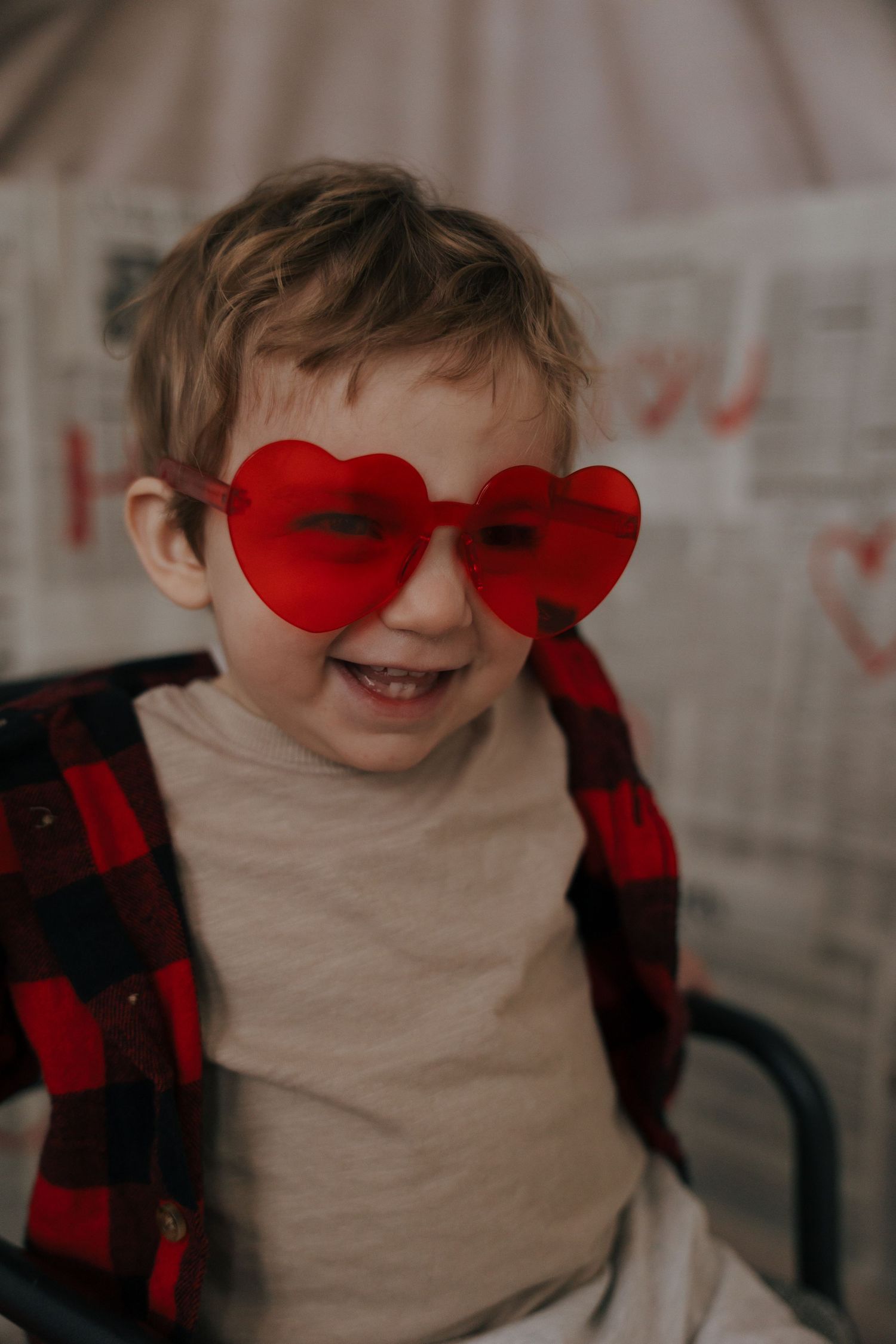 A series of photos showing someone wearing red heart-shaped sunglasses and a buffalo plaid shirt while smiling.