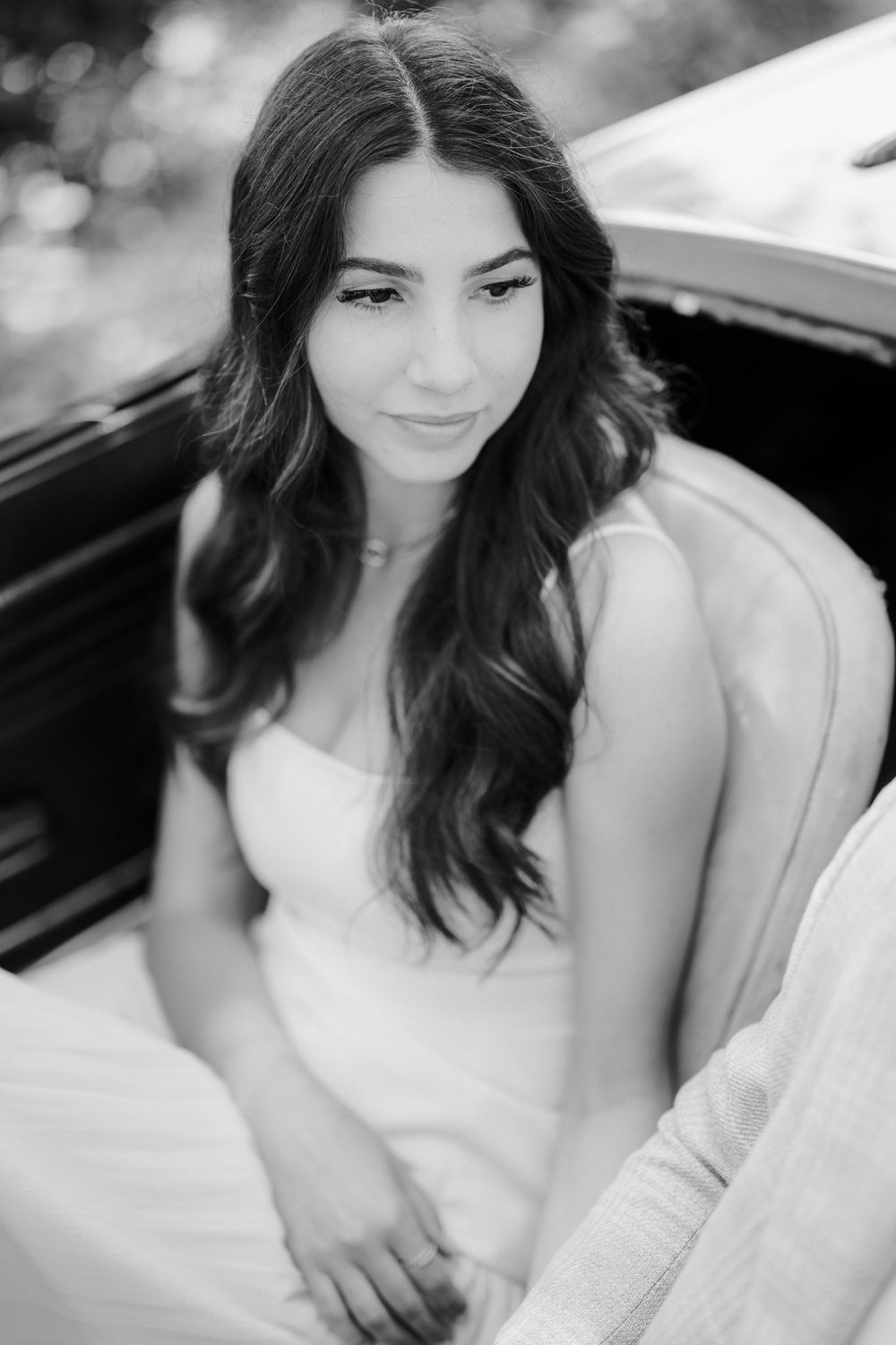 A black and white portrait series showing a woman in a white dress sitting in a car, captured from different angles.