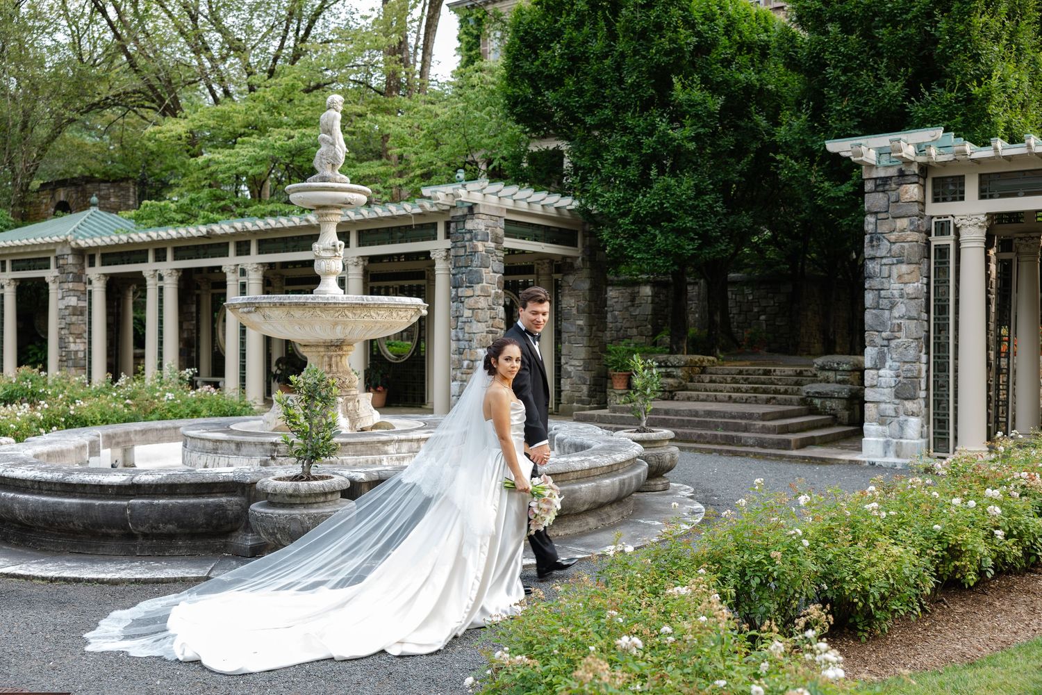 A panoramic view of an elegant stone wedding venue with landscaped gardens and a circular driveway.
