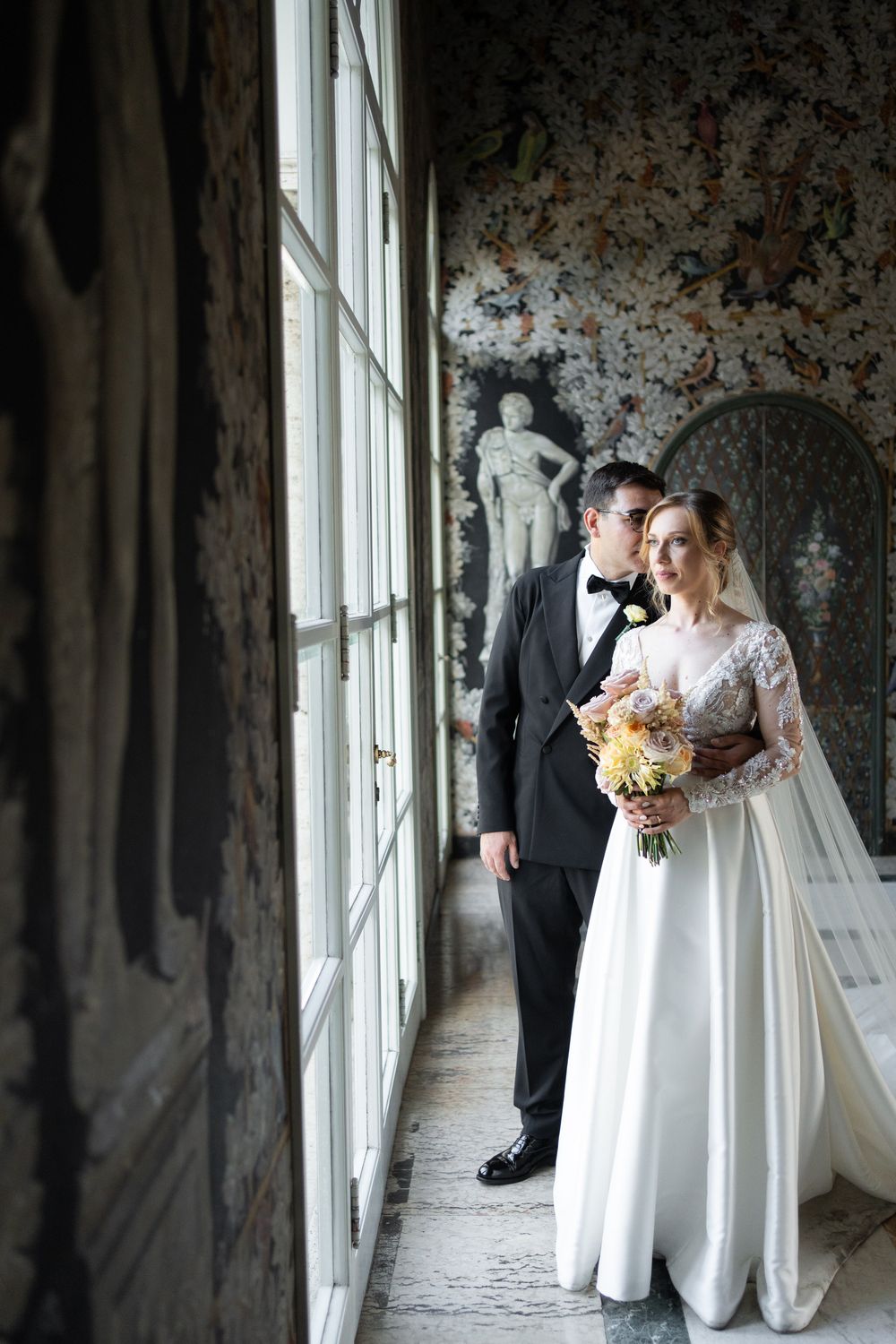 Bride and groom by a large window in a luxury wedding venue in Rome, soft natural light