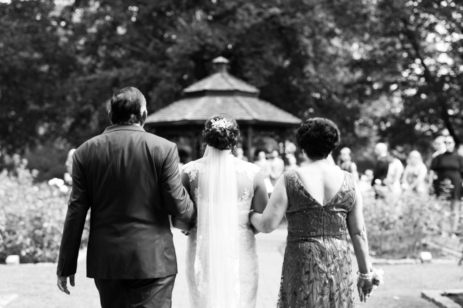 A black and white photo showing guests walking towards a gazebo at an outdoor event.