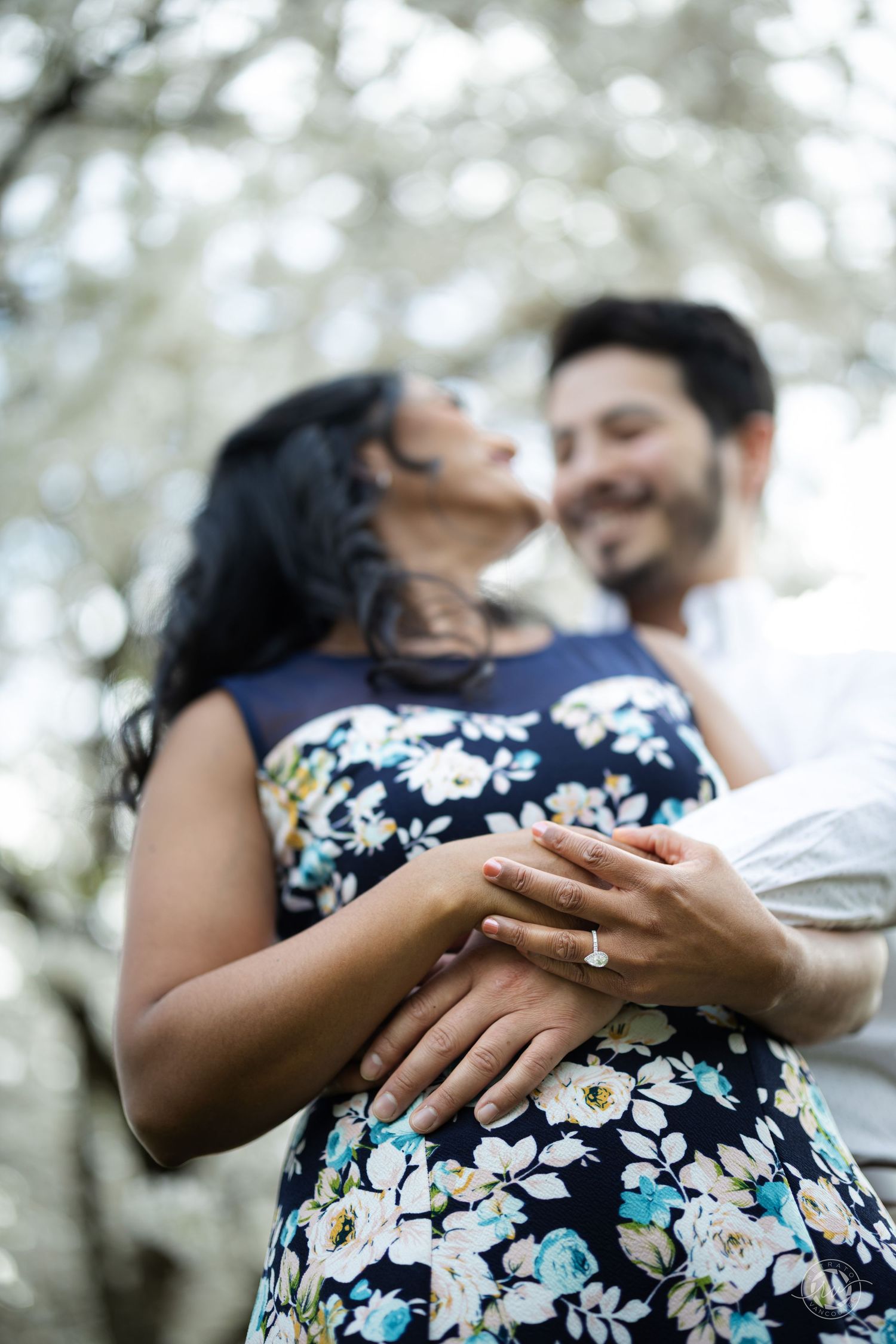 Close-up shots of hands touching during an outdoor engagement photo session with floral dress details.