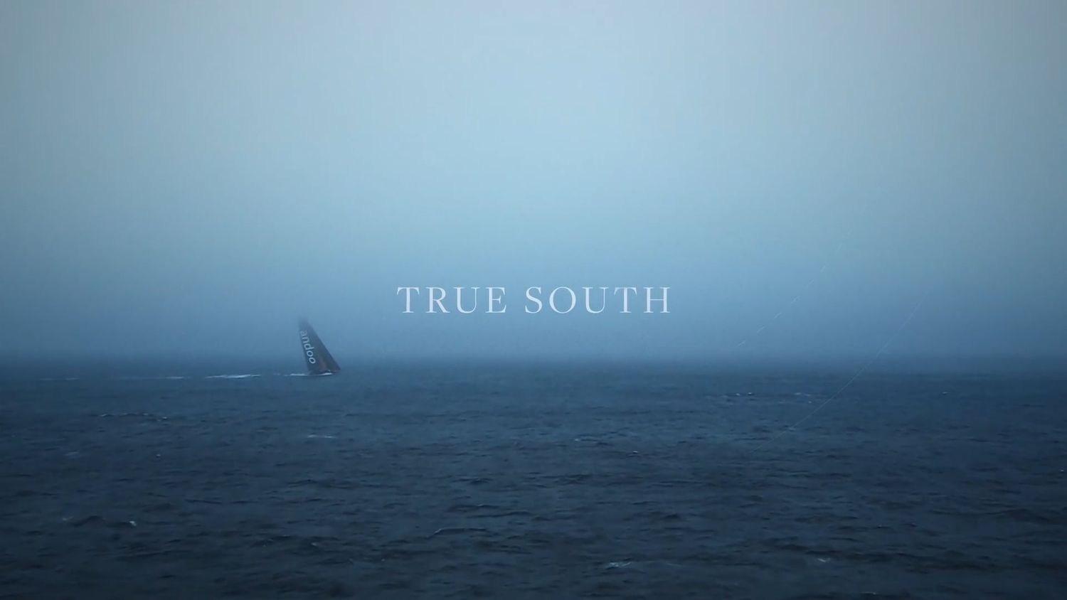 A sailboat silhouette on a misty ocean with 'True South' text overlaid on a moody blue-gray seascape.