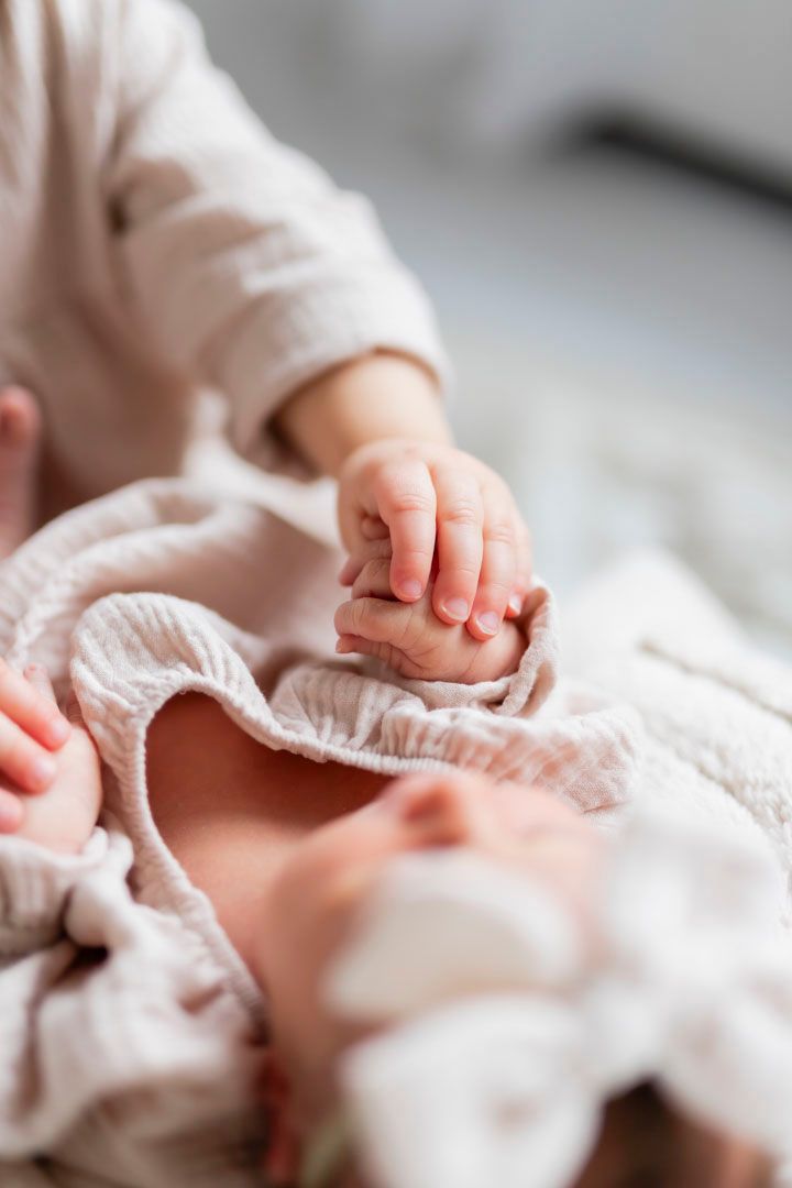 Isosisko pitää vauvan kädestä kiinni, ihanan yksityiskohta