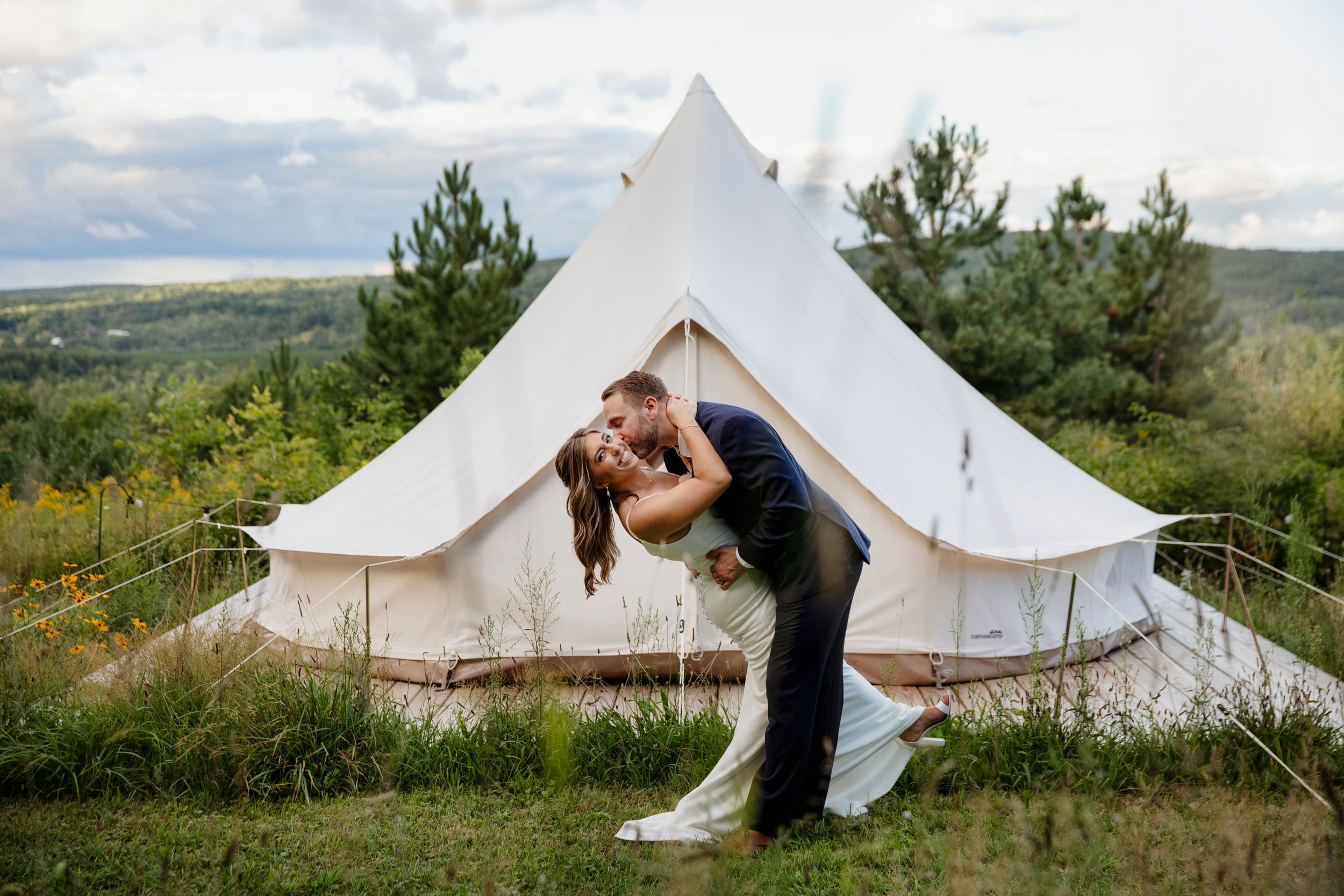 A romantic moment outside a bell tent glamping setup with scenic mountain views in the background in Boyne Falls Michigan at Lost Woods