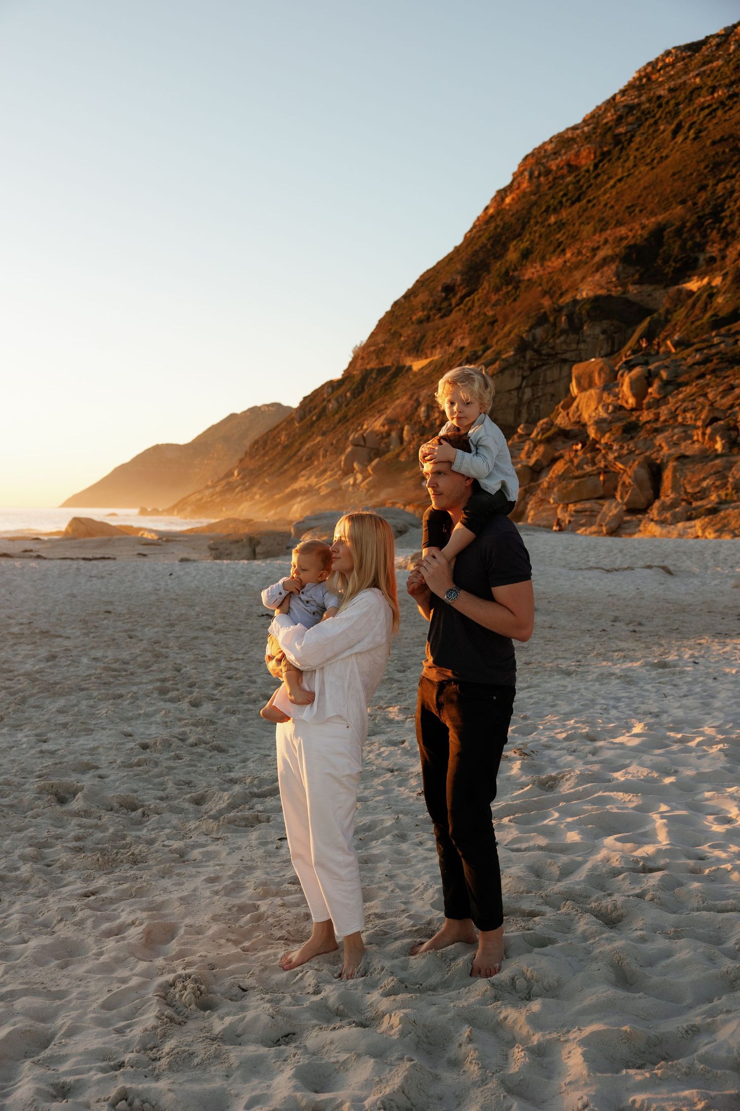 A family shares a tender sunset moment together while sitting on rocks outdoors.