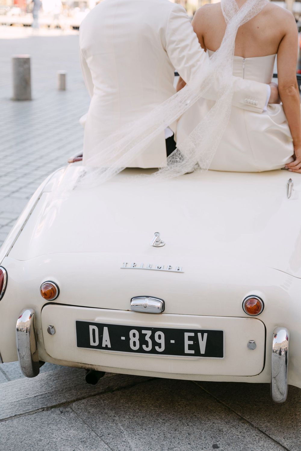 Close-up view of a vintage white car's rear end showing a license plate and classic rounded design details.