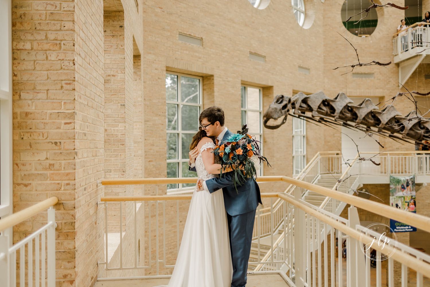Emotional first look between couple in a light-filled brick and white beam venue.