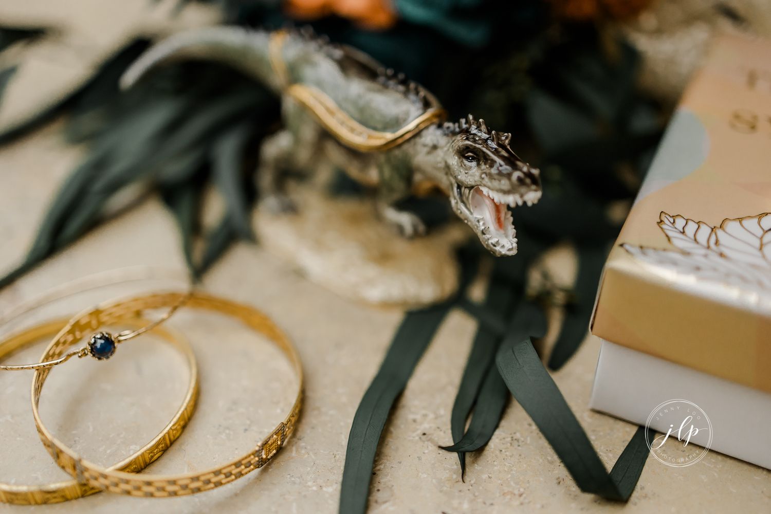 Artistically styled wedding rings with dark foliage accents.