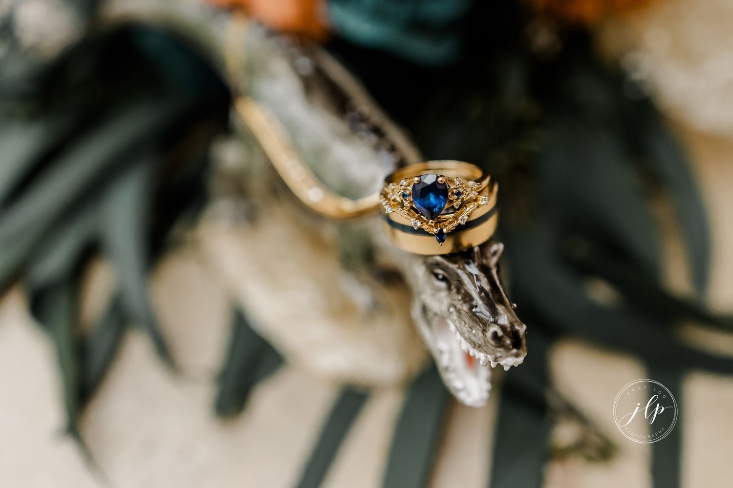 Artistic macro shot of wedding rings with dark foliage and decorative elements.