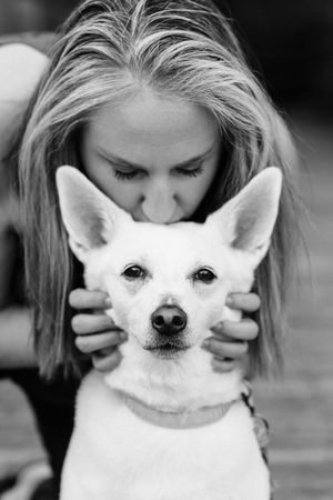 Black and white photo series of a small white Chihuahua dog peeking through a person's hands.