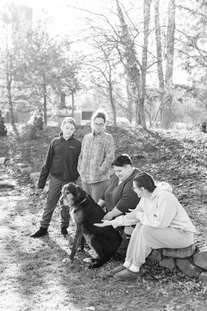 A black and white series showing a group of people relaxing on a hillside in an outdoor woodland setting.