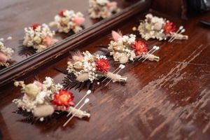 Wedding boutonnieres with dried flowers and coral accents arranged on dark wooden surface.