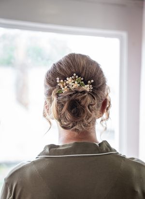 Elegant bridal updo hairstyle adorned with delicate crystal and pearl floral hair accessories seen from behind.