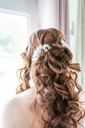 Elegant bridal hairstyle with curls and delicate white floral hair accessories.
