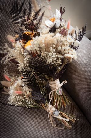 Rustic wedding bouquet featuring dried flowers, ferns and baby's breath tied with ribbon.