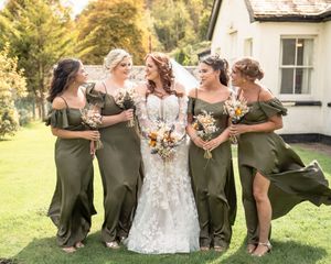 Bridal party in olive green dresses posing together on grassy lawn.