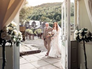 An elegant wedding couple shares their first dance in a light-filled porch surrounded by floral decorations.