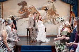 A joyous wedding celebration takes place in front of a vintage equestrian mural with guests seated on both sides.