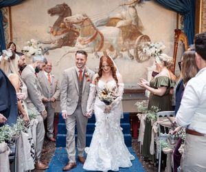 Wedding celebration scene with confetti being tossed at couple in elegant attire outside brick building.