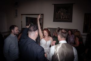 Wedding reception guests celebrating and dancing together in a dimly lit venue.