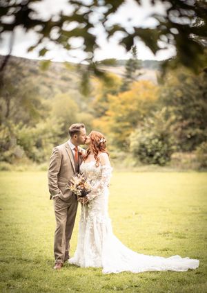 Romantic outdoor wedding photos taken in a scenic meadow with soft natural lighting and autumn foliage.