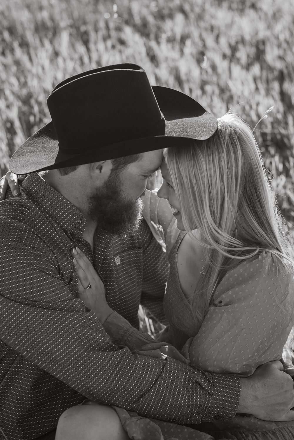 Intimate black and white portrait of couple sharing tender moment in rustic setting.