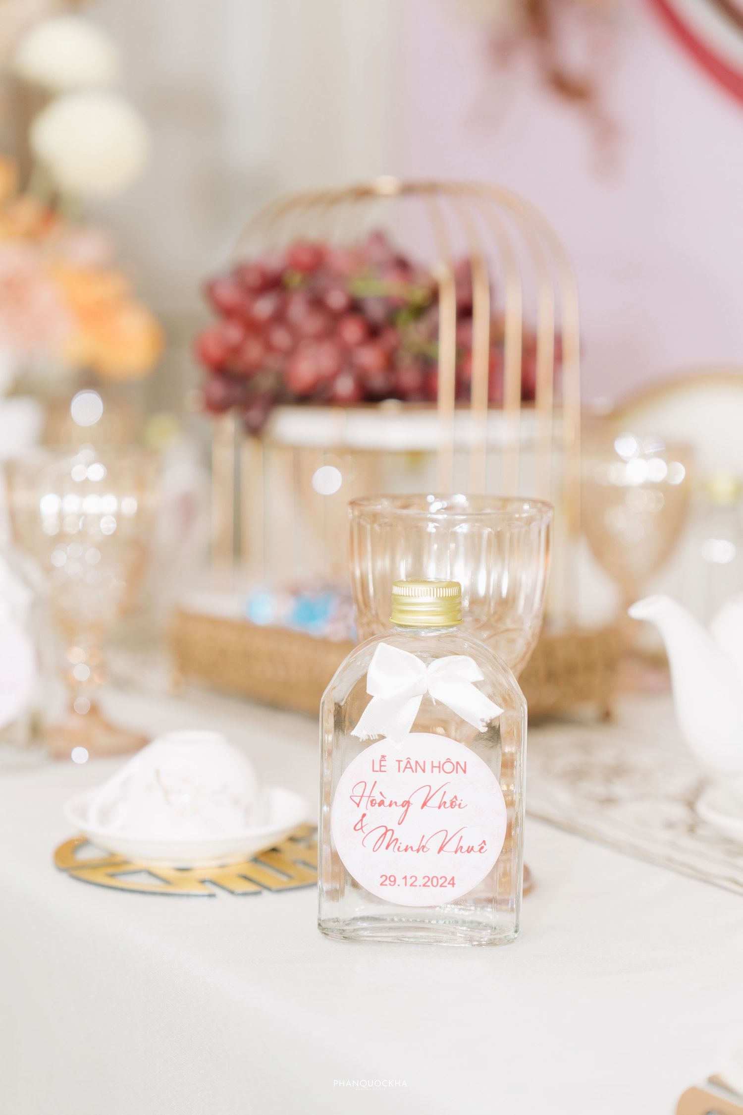 Glass bottle wedding favor with ribbon and custom label for Hoang Khoi and Minh Khue engagement.