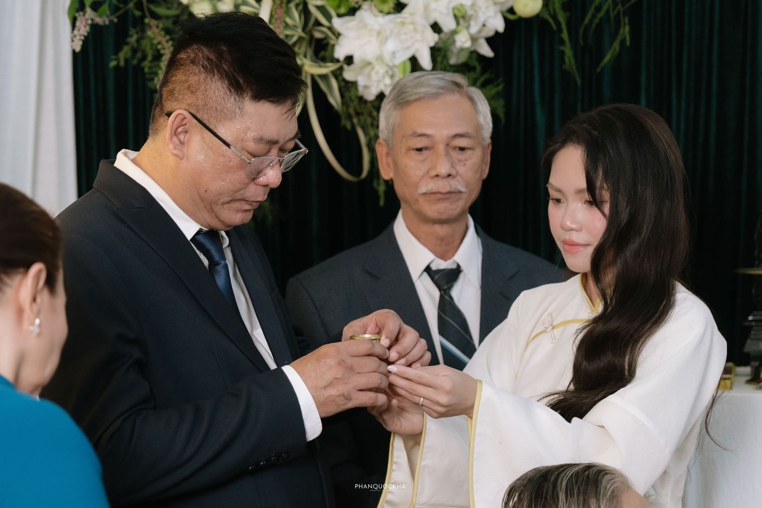 Close-up of father placing ring on daughters finger at traditional Vietnamese engagement ceremony.