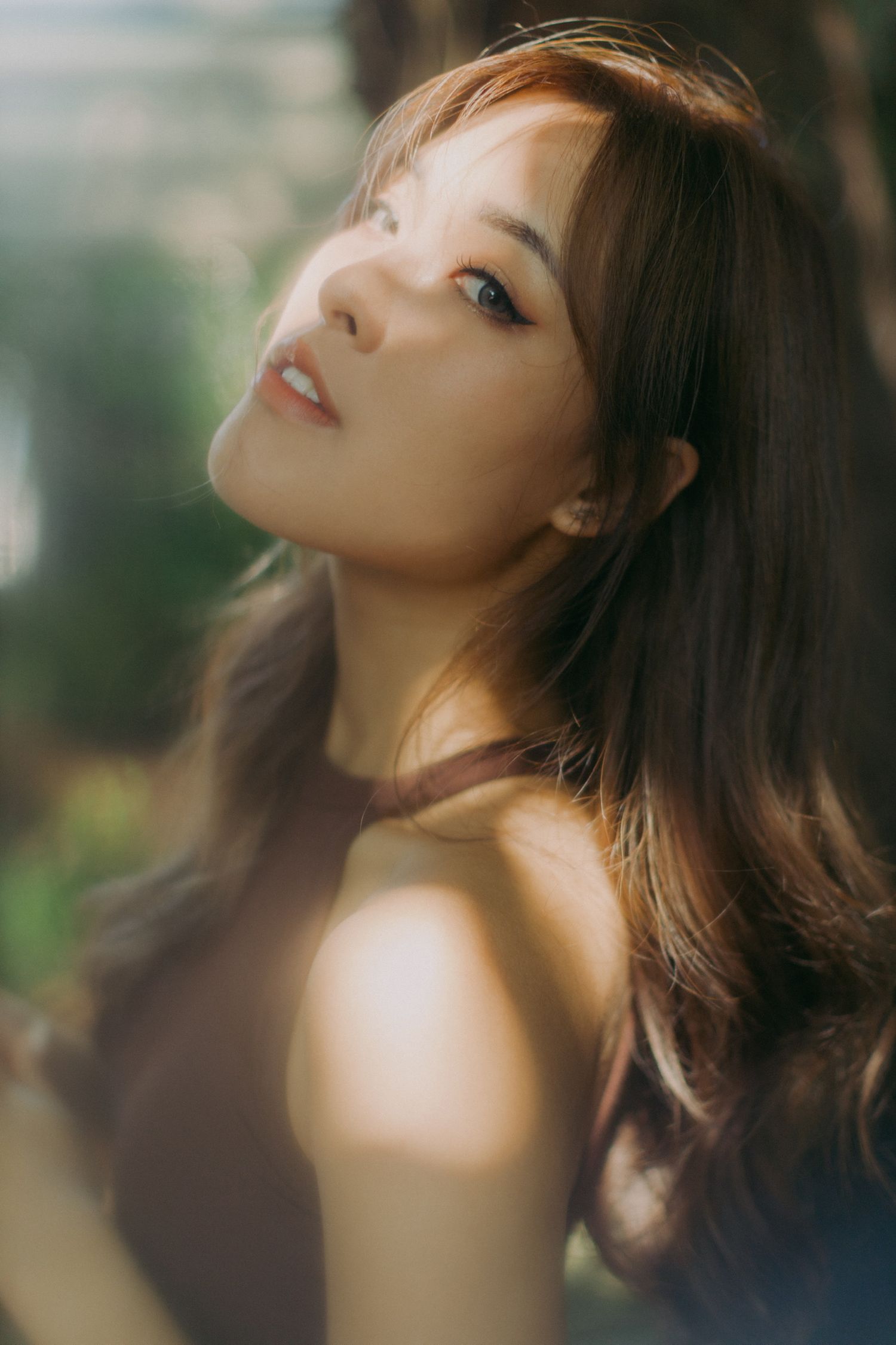 Woman in natural lighting with soft makeup gazing upward dreamingly.