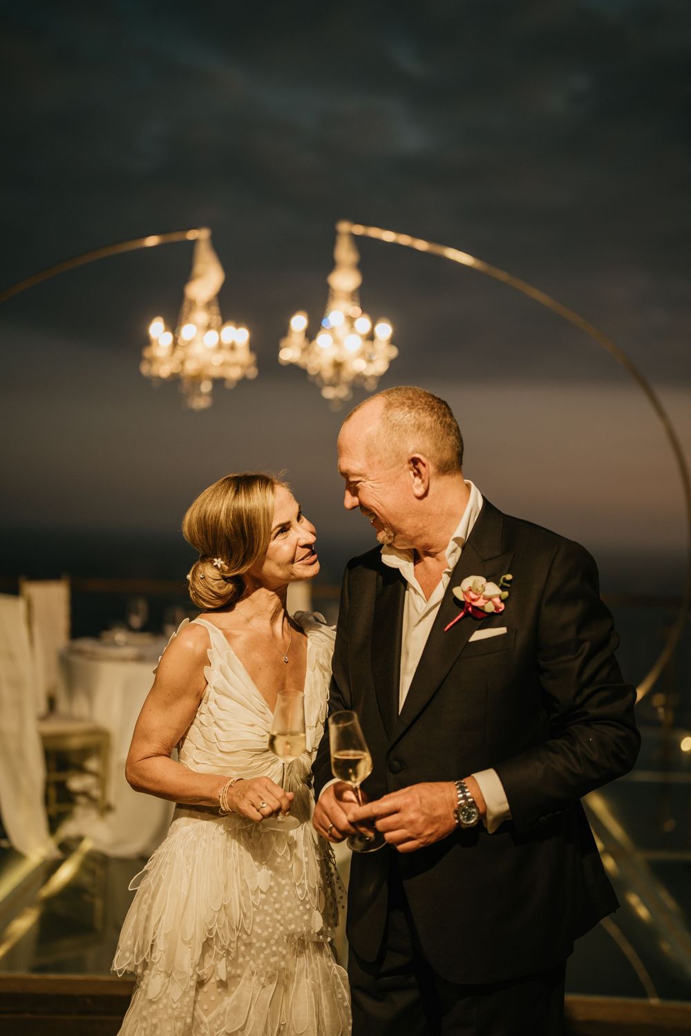Evening reception scene with couple sharing intimate moment under arched lighting fixtures.