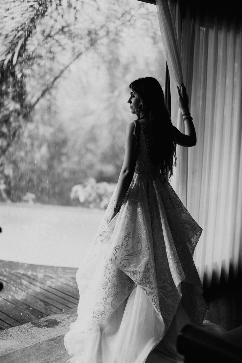 Black and white silhouette of a wedding dress against natural window light.