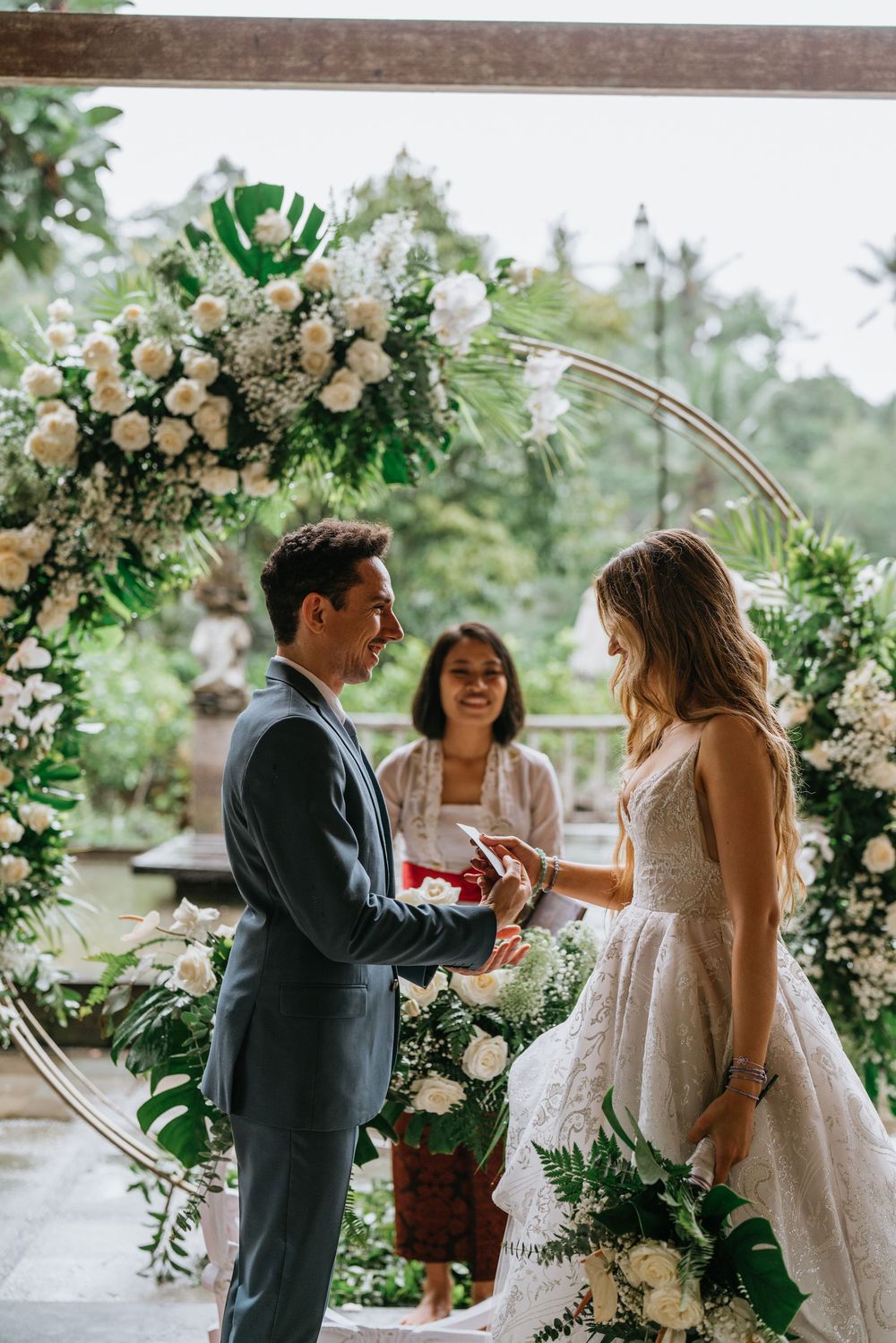 Beautiful floral arch with white roses and greenery framing a wedding ceremony moment.