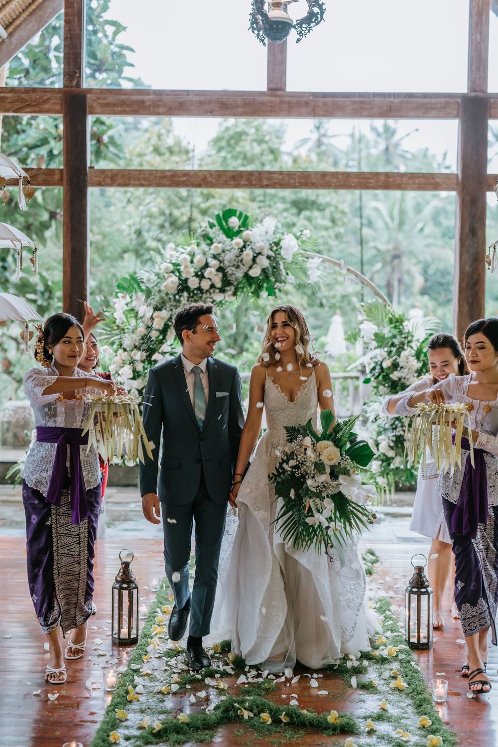 Wedding guests gathered in an elegant venue decorated with greenery and lanterns.