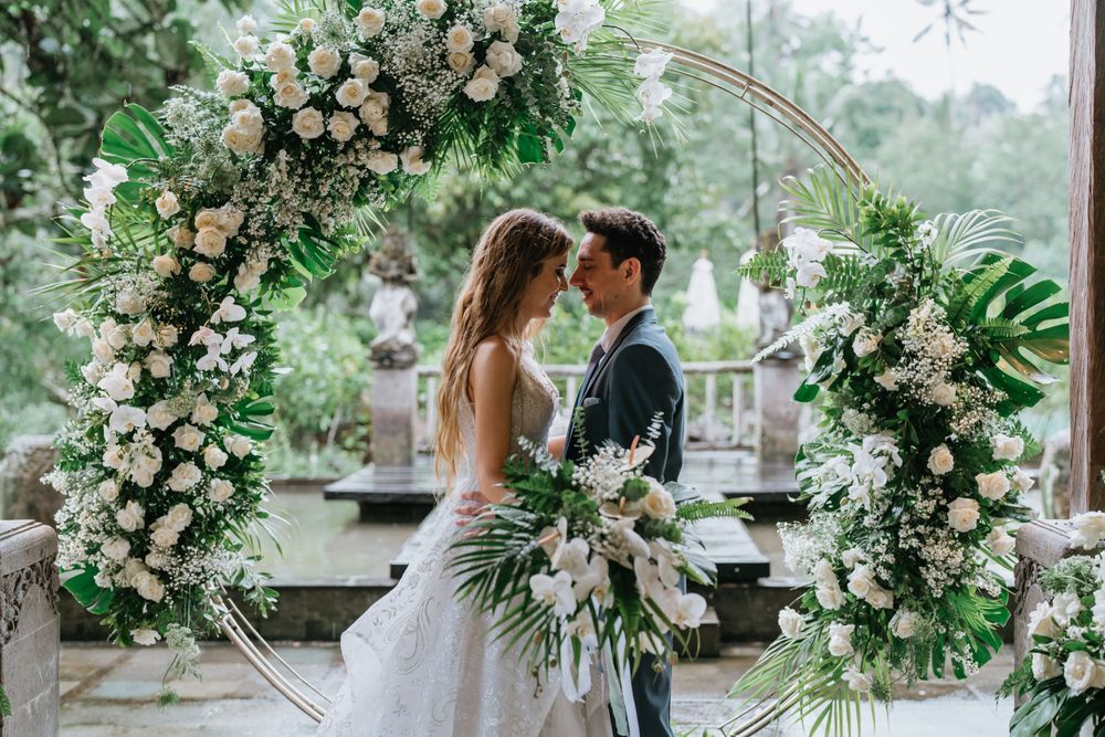 Romantic wedding ceremony setup with lush floral arches and greenery in an elegant outdoor venue.