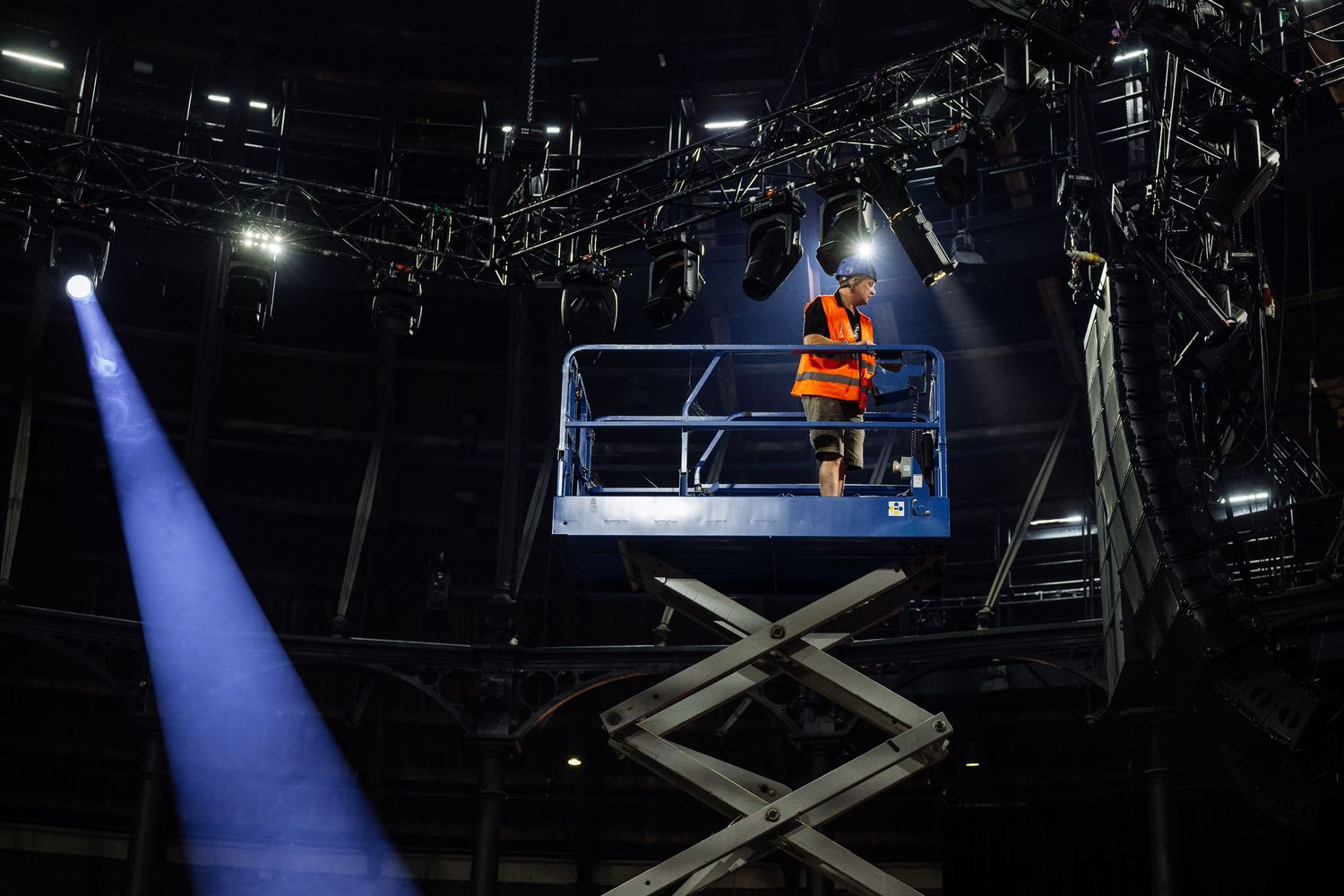 Stage lighting equipment and rigging mounted on dark theater ceiling.