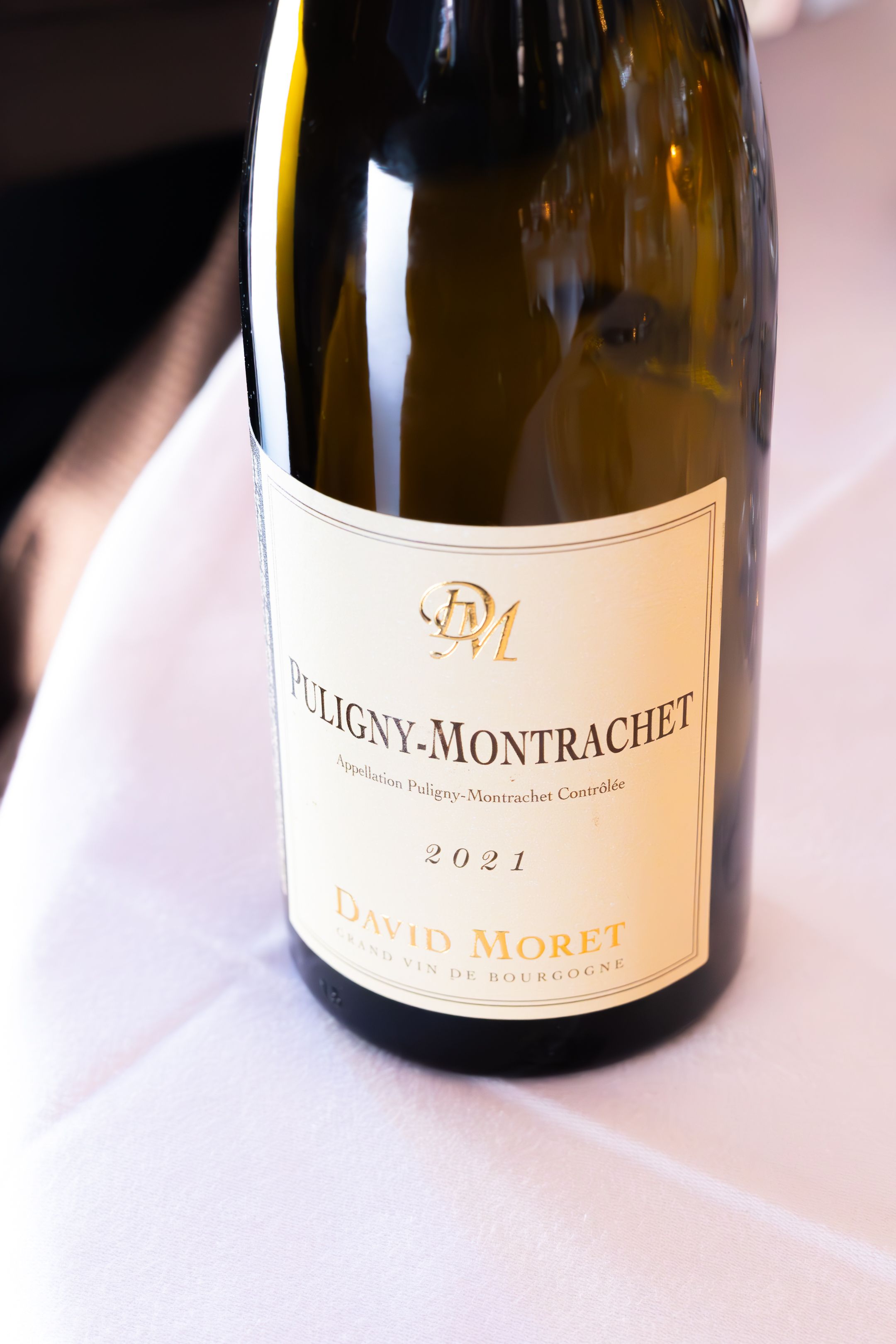 Several bottles of Puligny-Montrachet wine displayed on a white tablecloth.