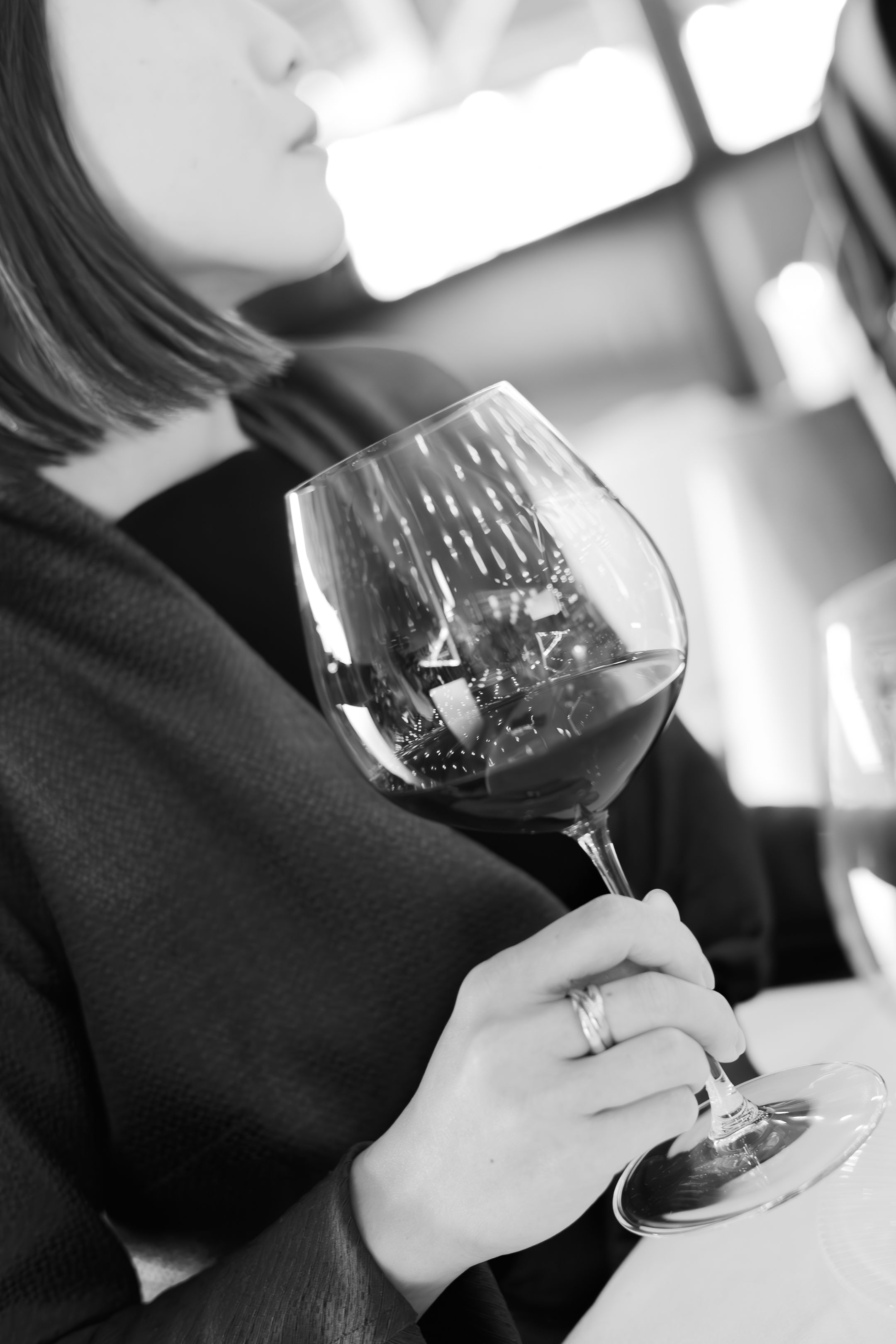 A black and white photo series showing hands holding and swirling a glass of red wine against a blurred background.