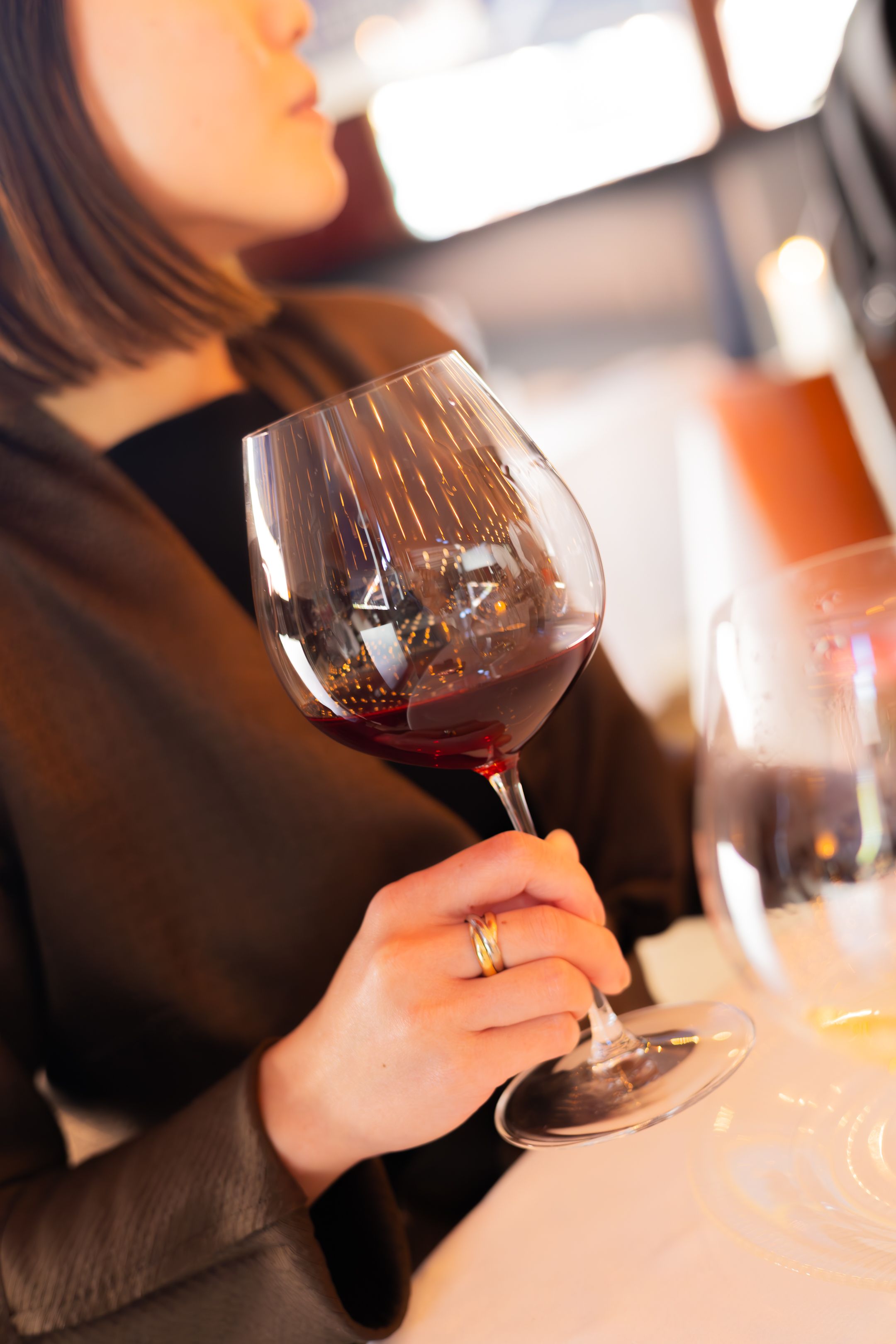 Hands holding red wine glasses in a dimly lit restaurant setting.