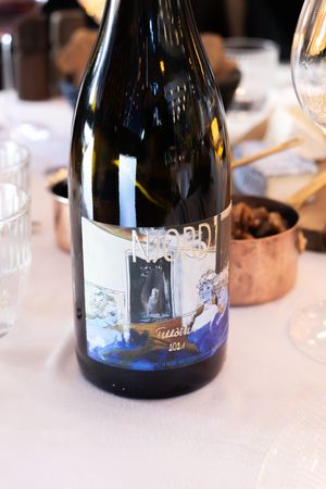 Multiple wine bottles with blue labels arranged in a row on a table showing a collection of fine wines.
