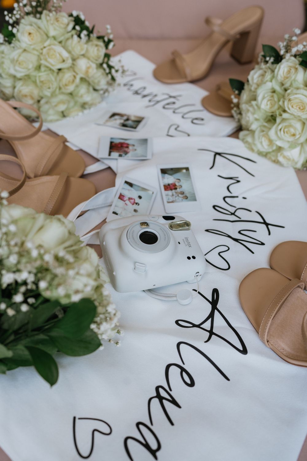 Wedding detail shot of white roses and handwritten calligraphy on table.