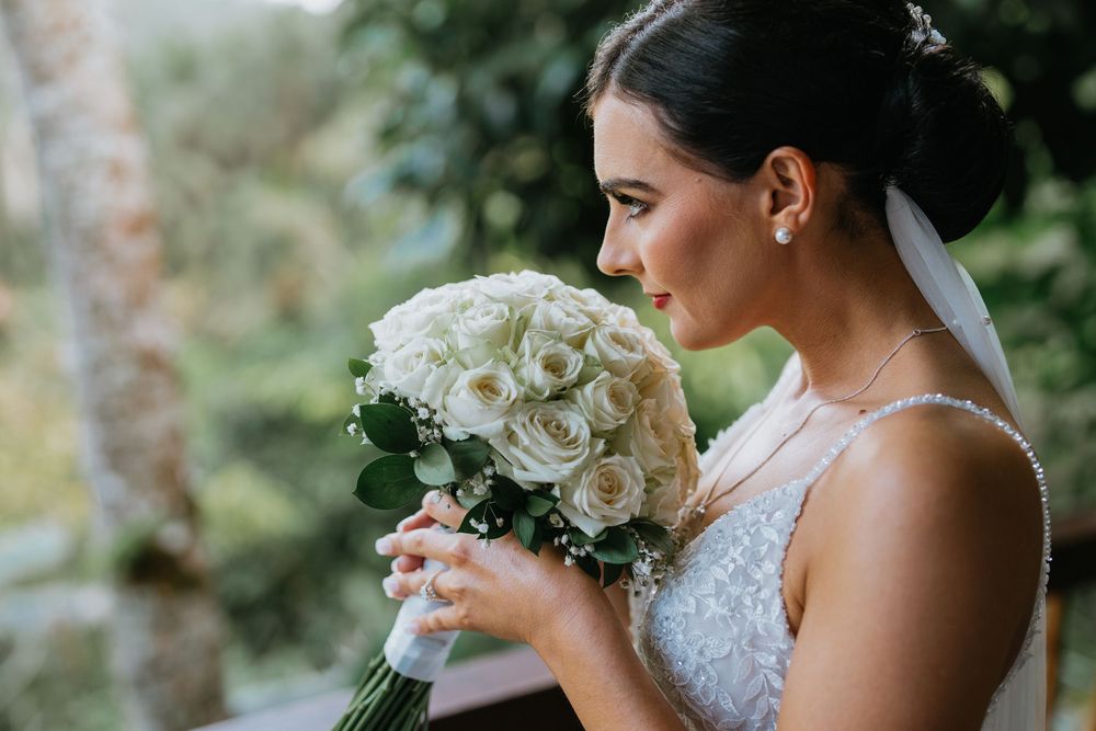 Bride holds elegant white rose bouquet during outdoor portrait session.