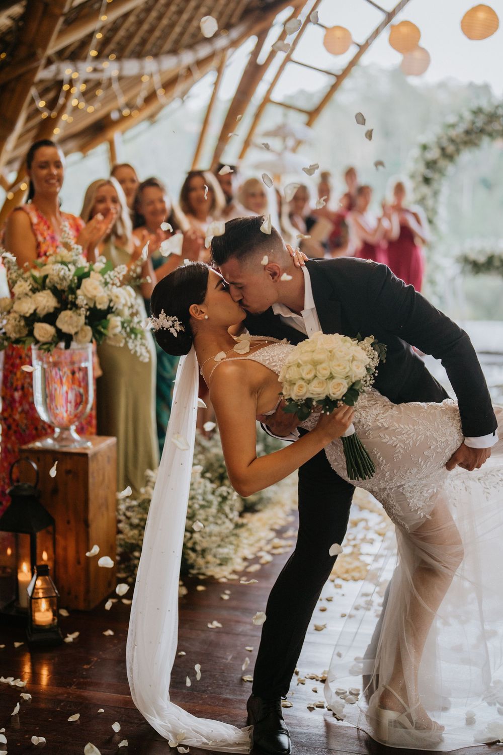 Romantic wedding kiss sequence with floral decorations and guests in background.