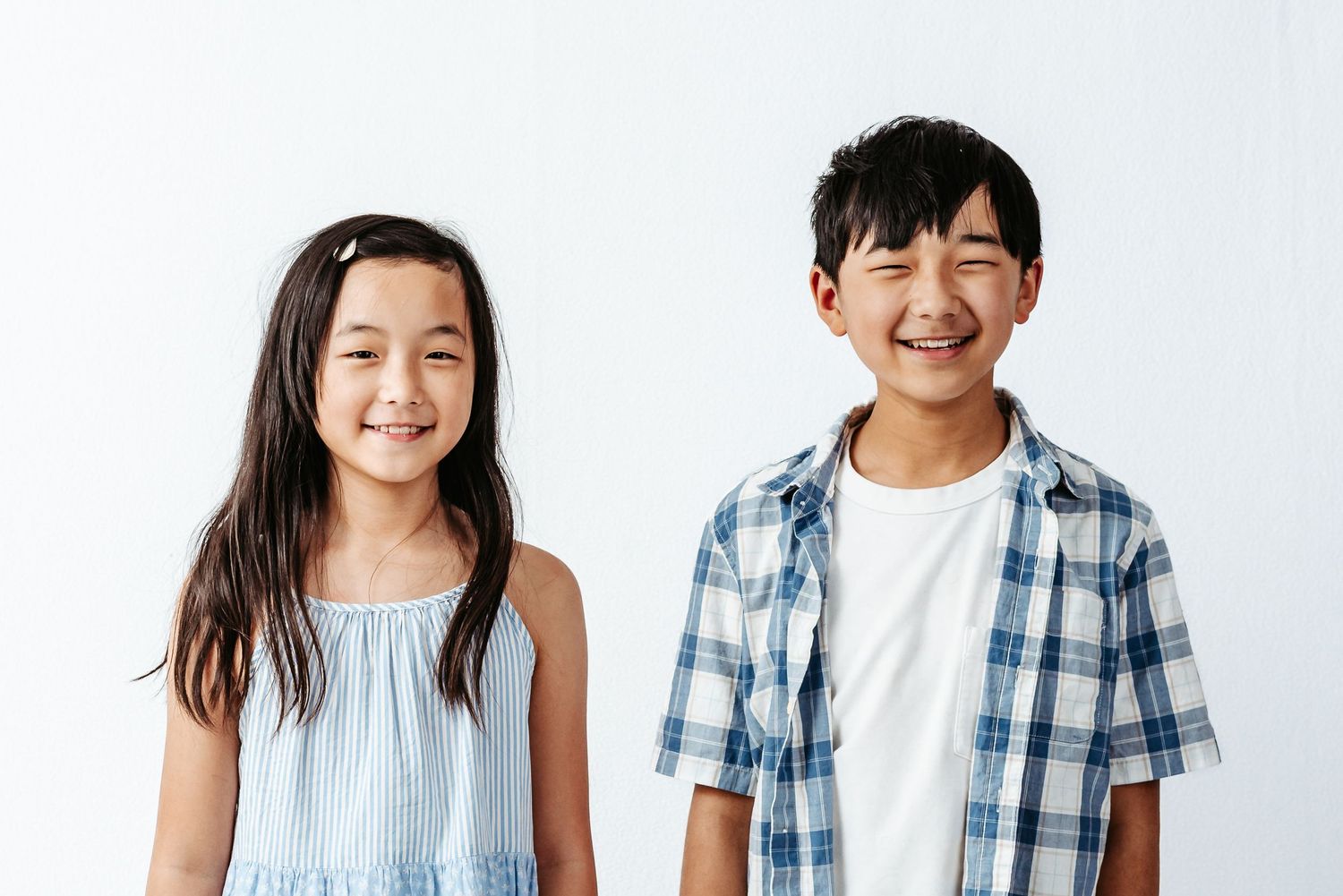 Five children stand in a row wearing casual blue and white summer outfits with bright smiles.