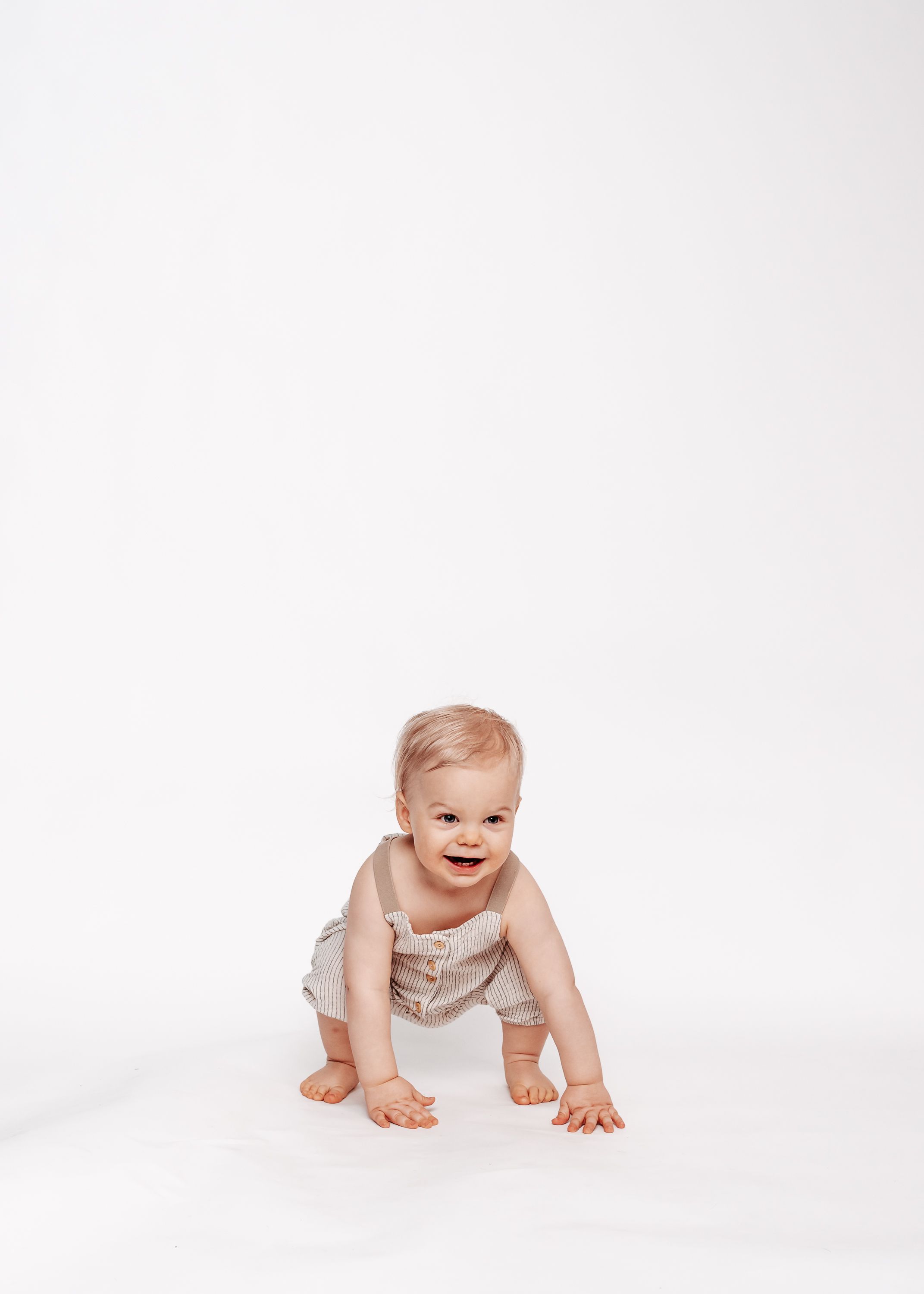 A crawling baby wearing white on a clean white background.