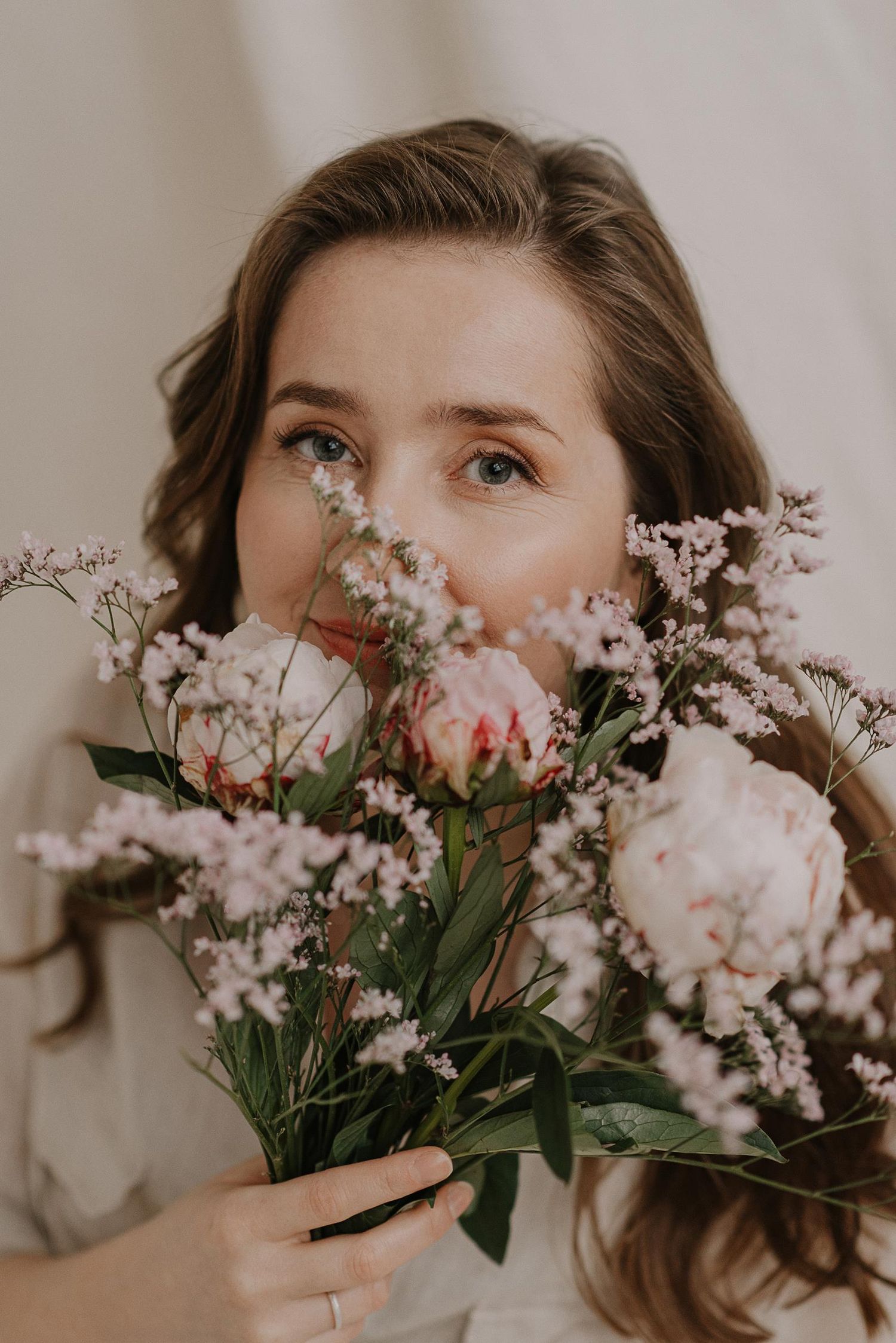 Dreamy portrait with soft pink flowers creating a romantic hiding effect.