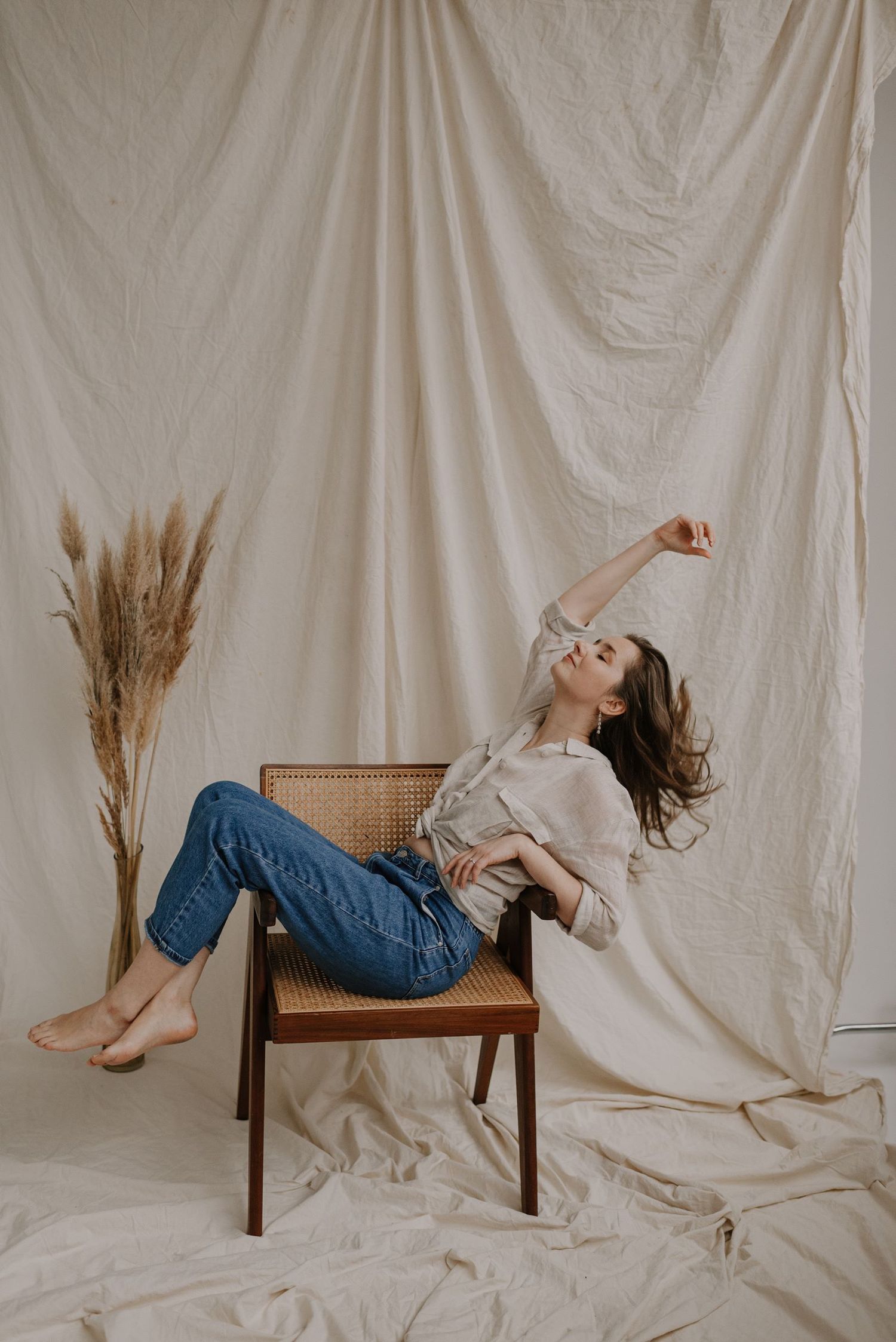 Dynamic poses on cane chair with wheat stalks against white backdrop.
