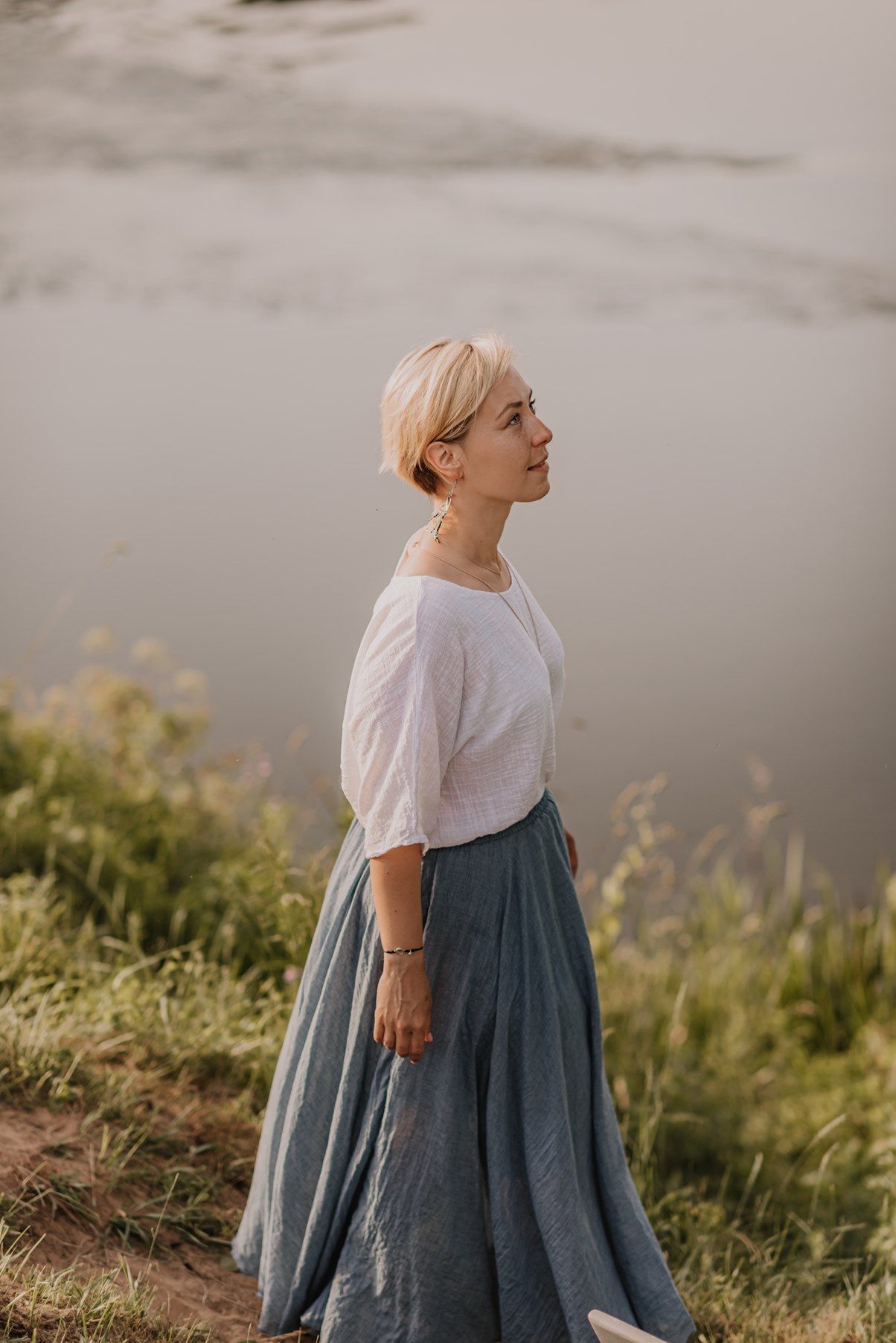 Ethereal outdoor portrait in white and blue dress against moody sky.